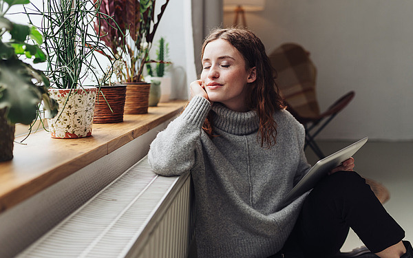 Frau sitzt am Fenster und blickt nach draußen.