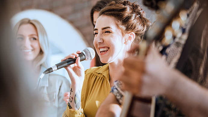 Junge Frau singt in ein Mikrofon