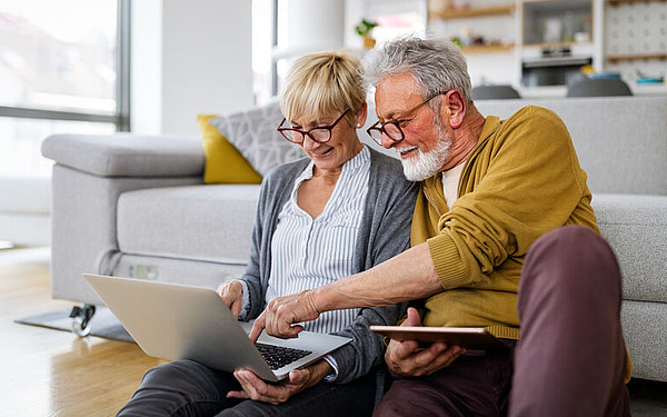 Älteres Ehepaar schaut gemeinsam auf einen Laptop.