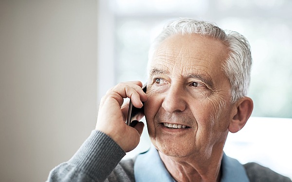 Männlicher Rentner telefoniert.