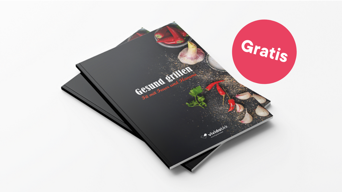 Zwei Rezepthefte mit frischem Gemüse auf dem Umschlag sind auf einer weißen Fläche gestapelt. Der Umschlagtext lautet "Gesund Grillen". Ein rosa runder Aufkleber mit der Aufschrift "Gratis" befindet sich oben rechts auf den Heften.